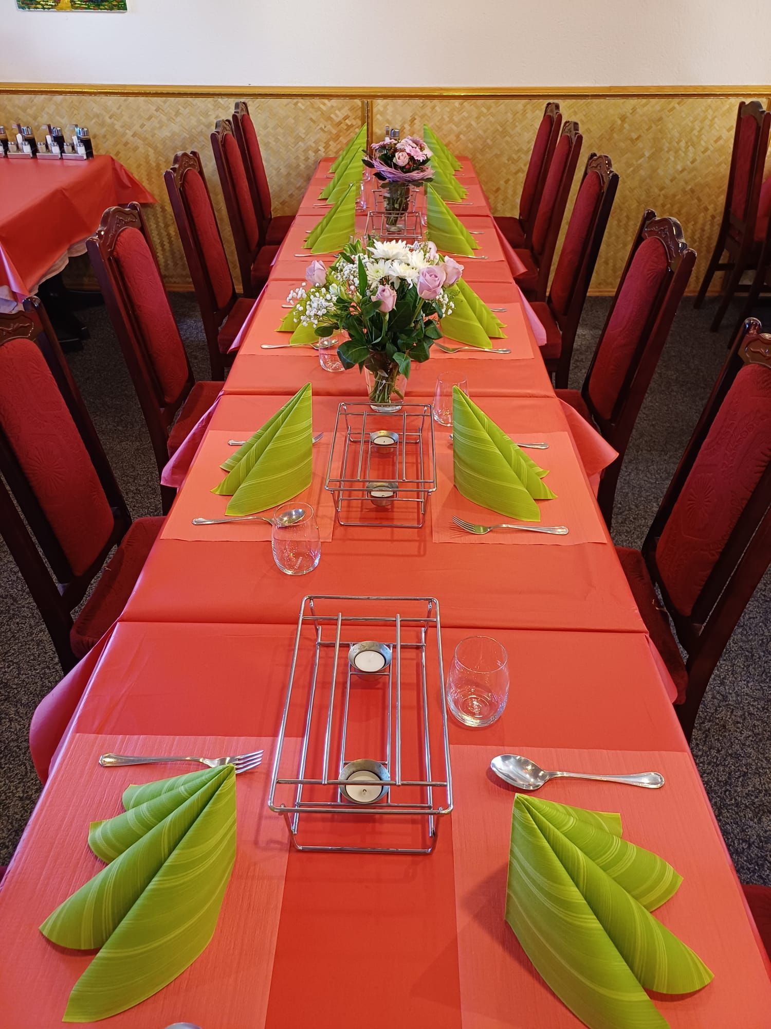 Ein langer Tisch mit grünen Servietten und Blumen darauf