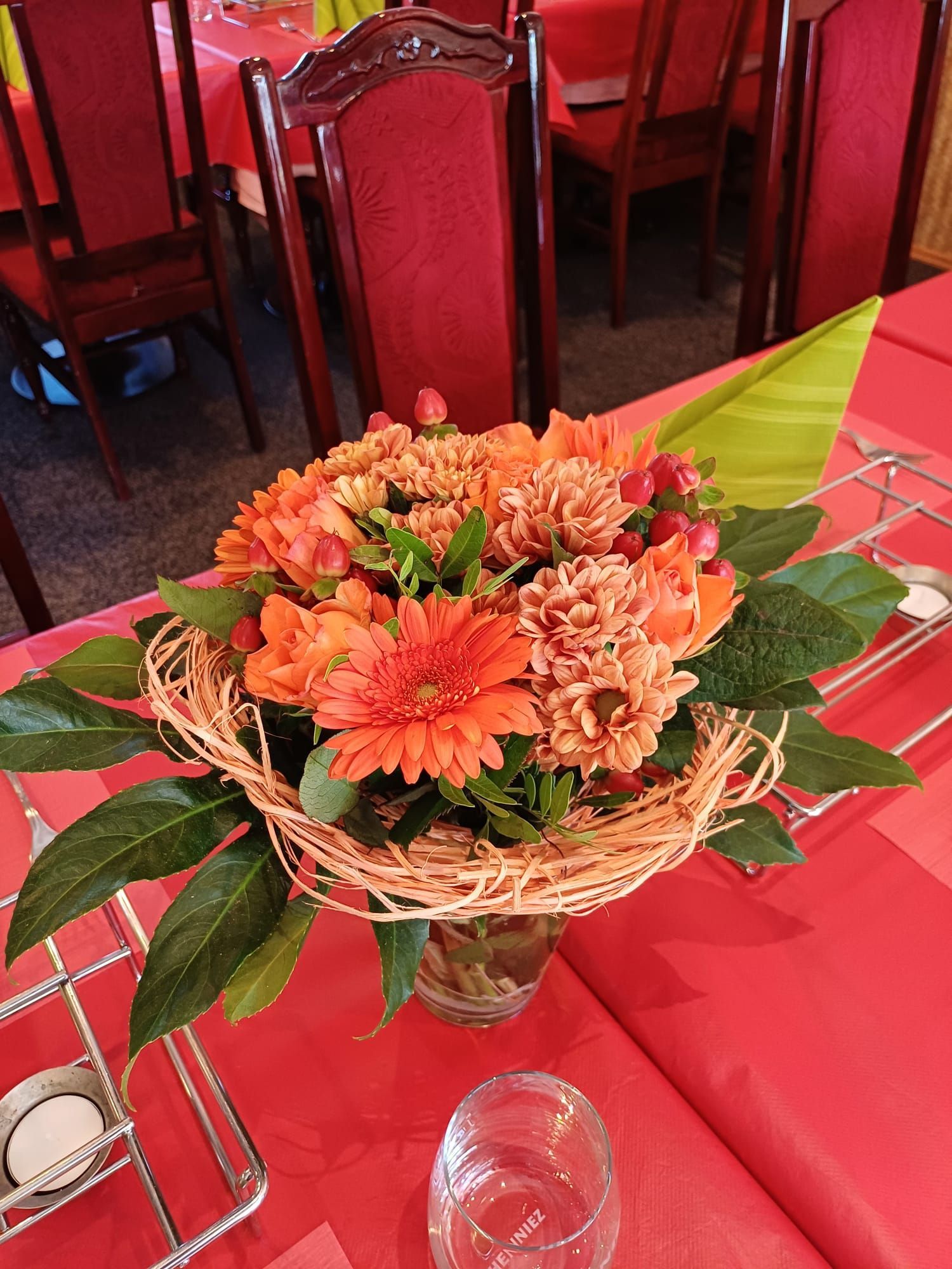 Ein Strauß orangefarbener Blumen in einer Vase auf einem Tisch.