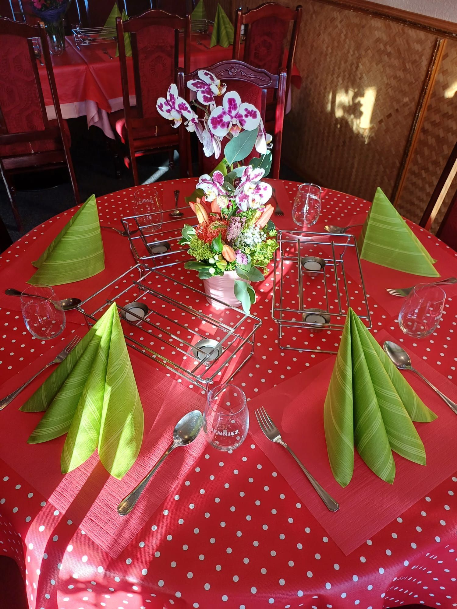Eine rote Tischdecke mit grünen Servietten und Besteck darauf