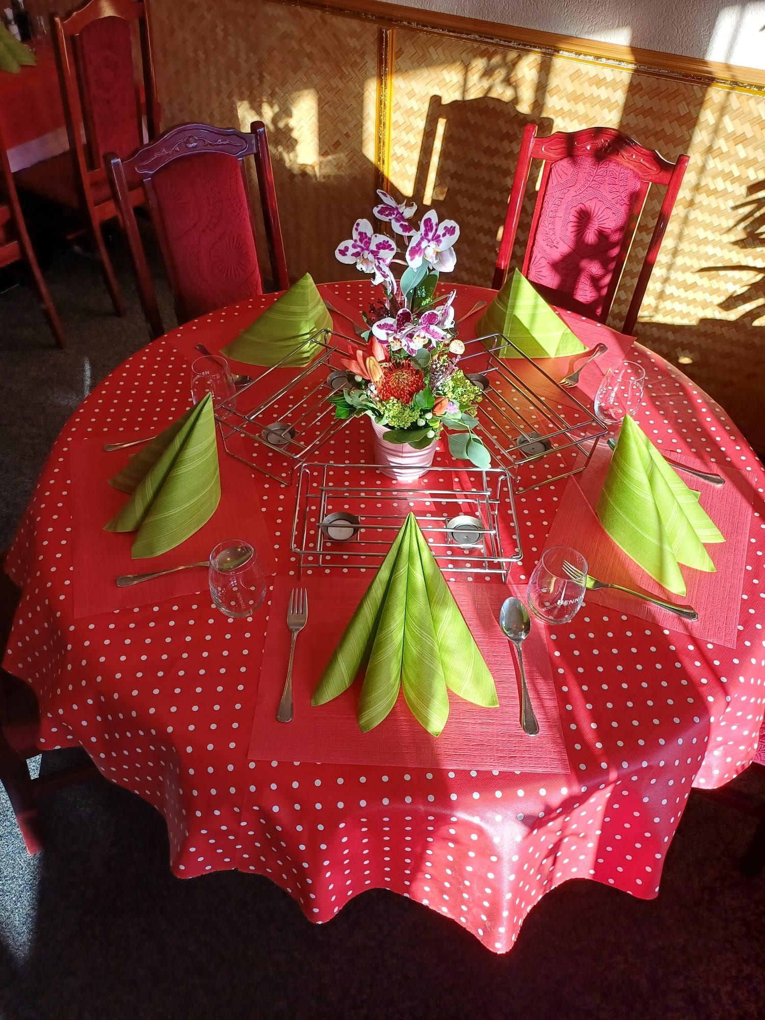 Ein runder Tisch mit roter Tischdecke und grünen Servietten