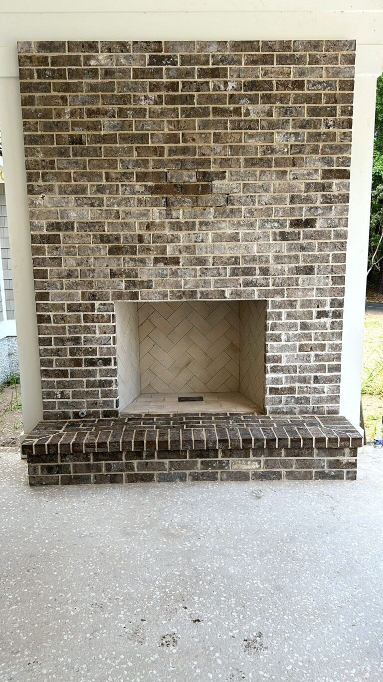 A large brick fireplace is sitting on top of a concrete patio.