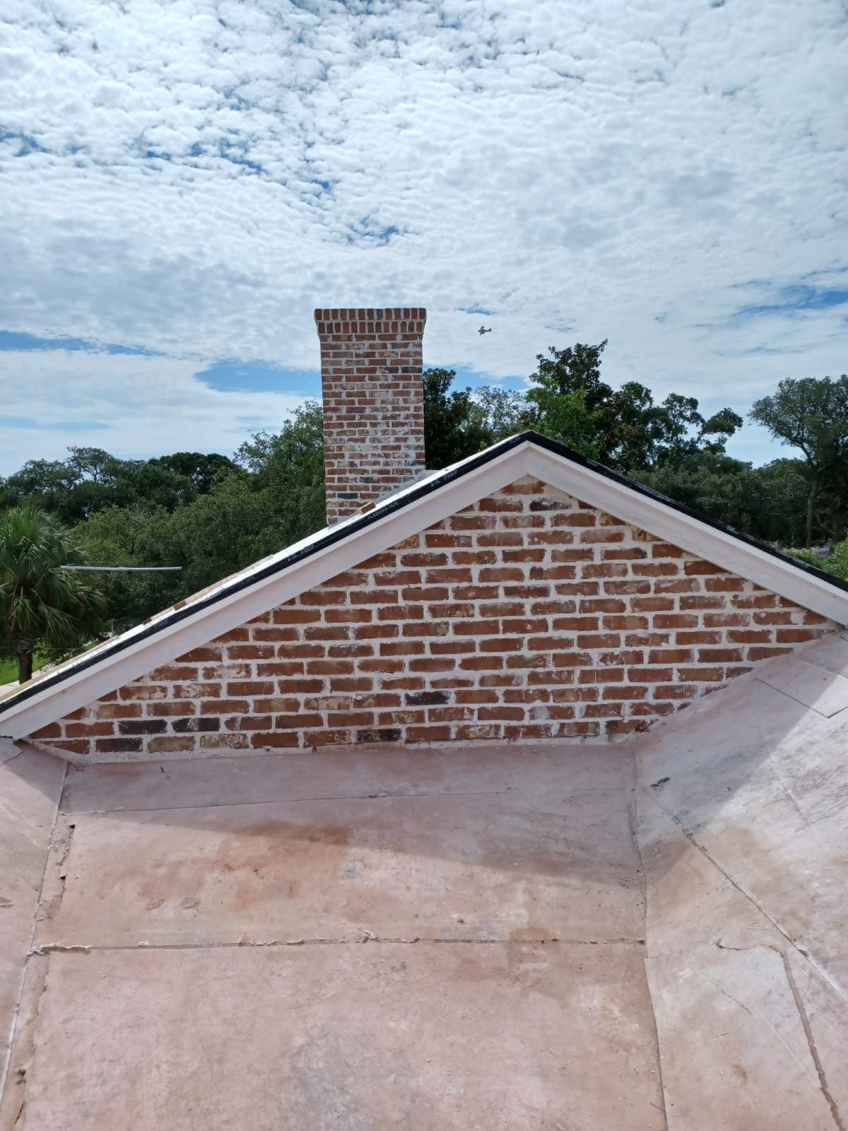 A brick chimney is on the roof of a house.