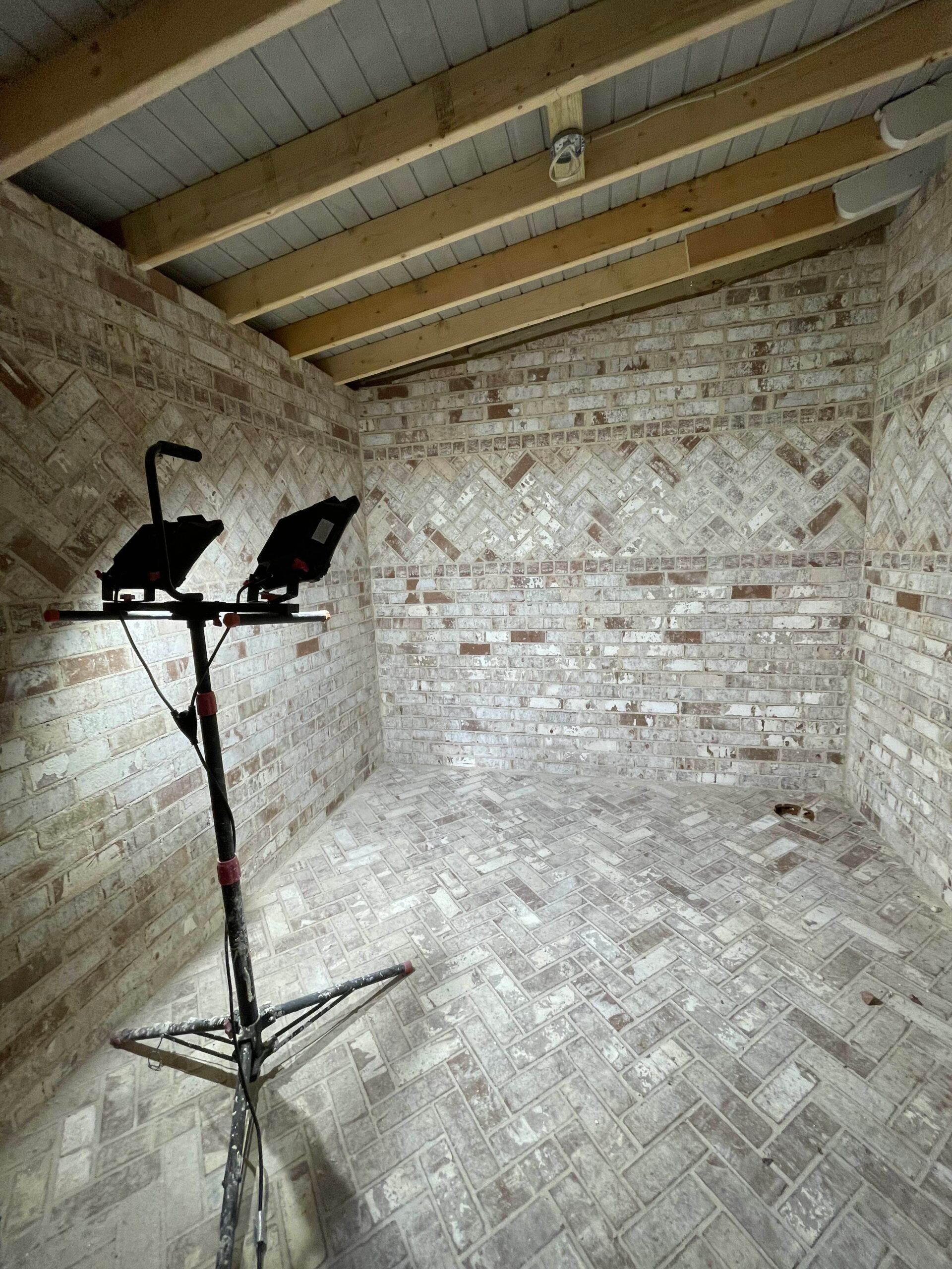 A room with a brick wall and two lights on a tripod.