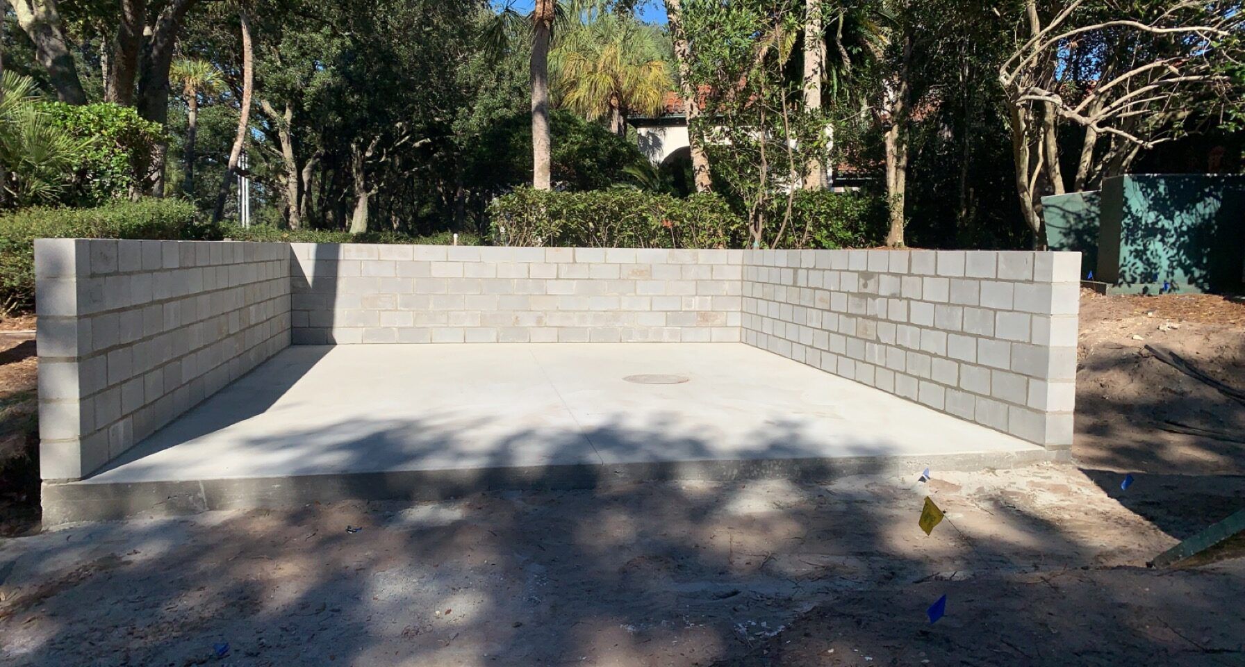 A concrete block wall is being built in a backyard.