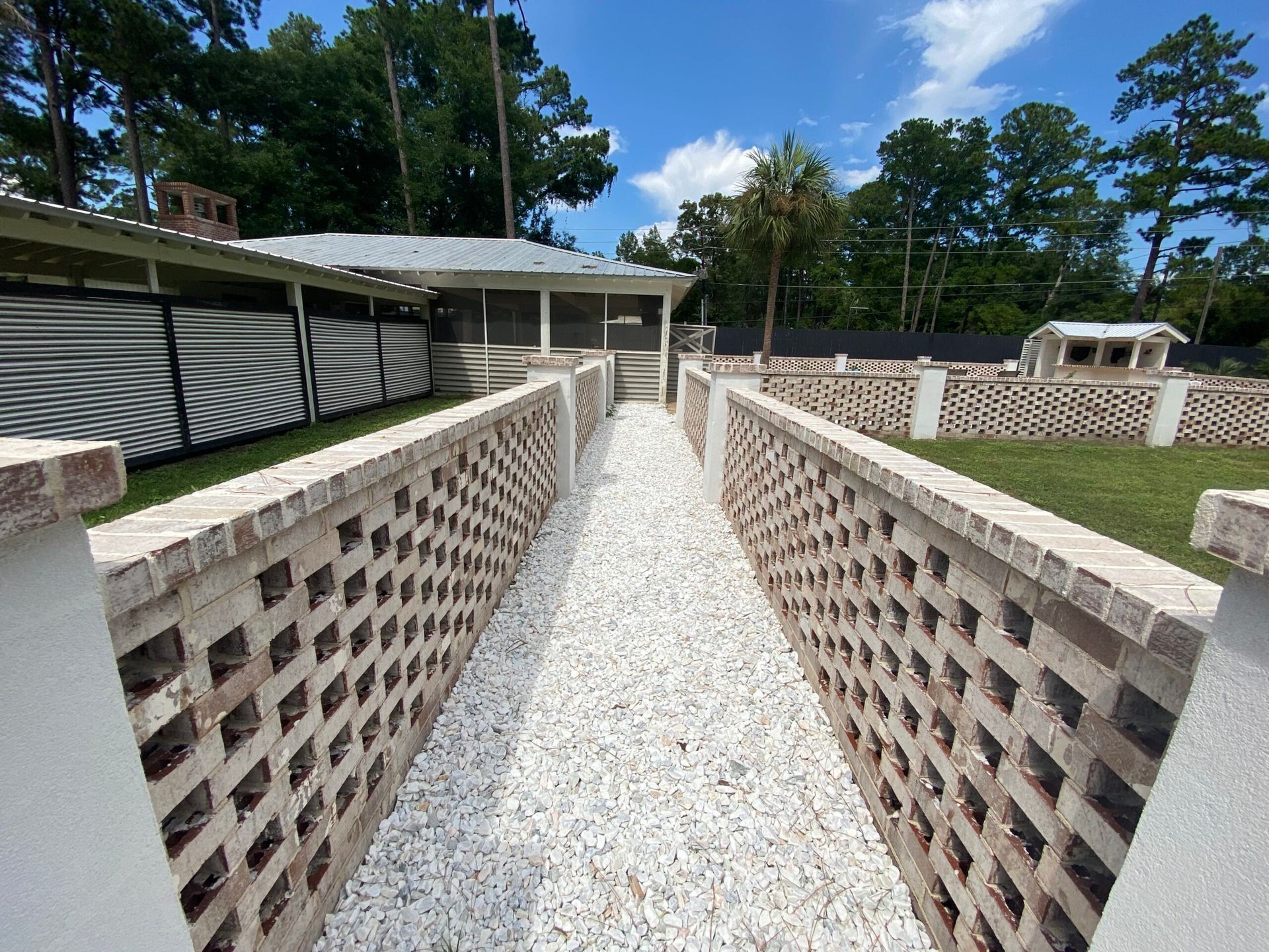 A brick walkway leading to a house with trees in the background