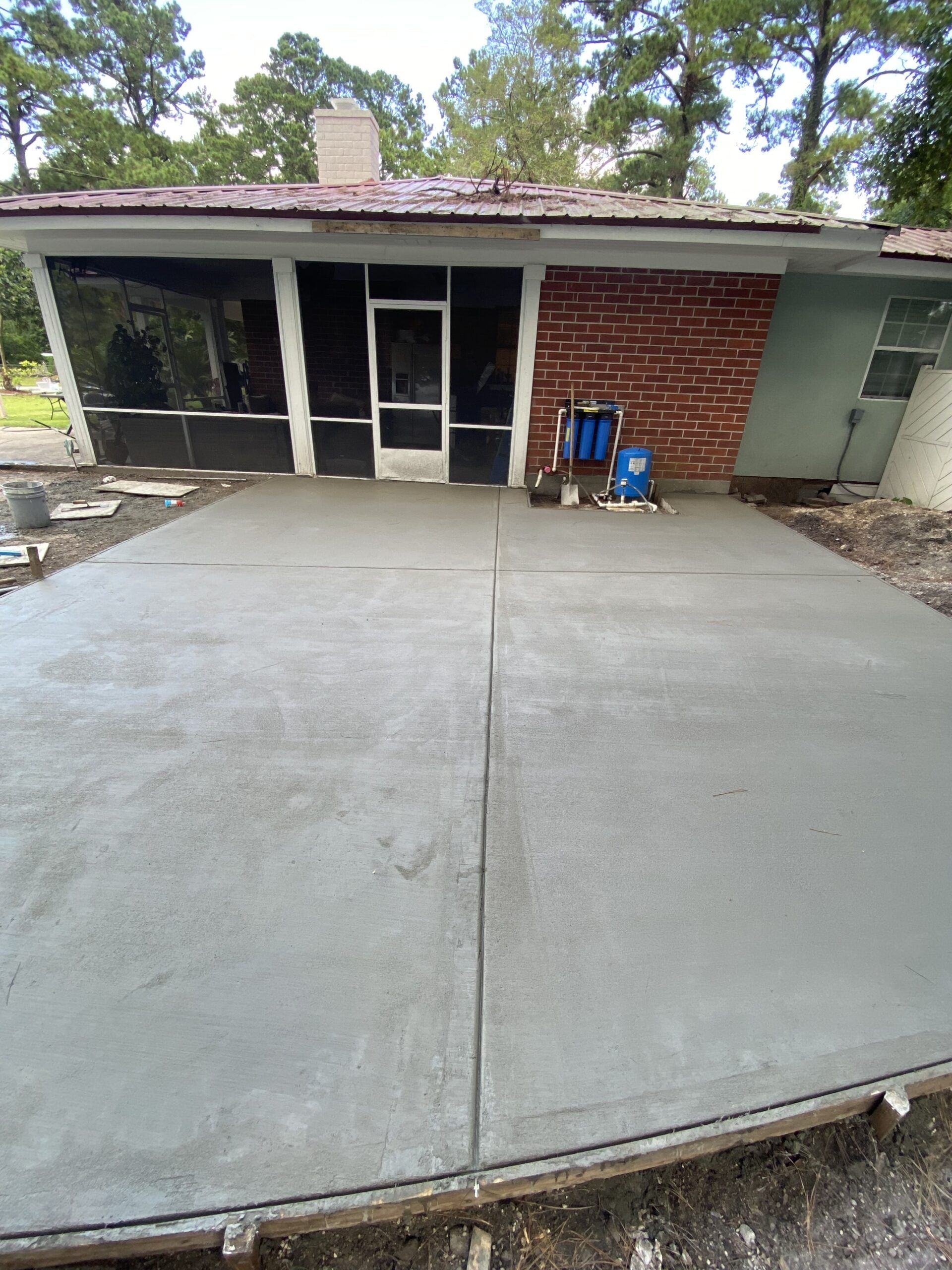 A concrete driveway is being built in front of a brick house.