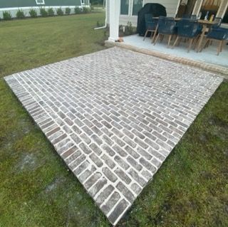 A large brick patio with a dining table and chairs in the background.
