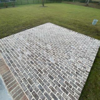 A large brick walkway is sitting in the middle of a lush green field.