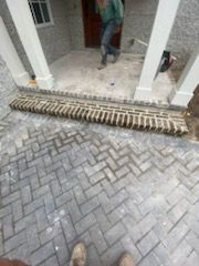 A person is standing on a brick walkway in front of a house.