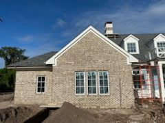 A large brick house is being built with a lot of windows.