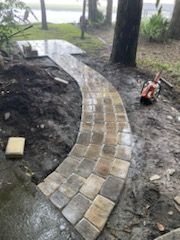 A brick walkway is being built in a backyard.