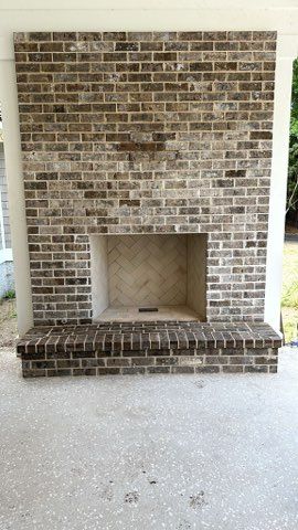 A large brick fireplace is sitting on top of a concrete patio.