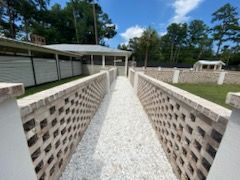 A walkway leading to a house with a fence and gravel.