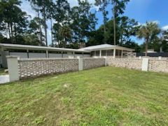 A mobile home with a fence in front of it and trees in the background.
