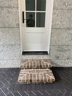 A white door is sitting on top of a set of brick steps.