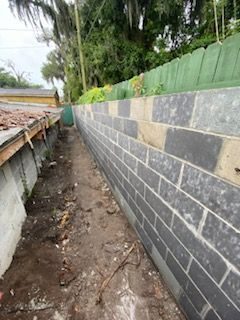 A long brick wall is being built next to a house.