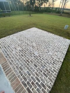A large brick pavement is sitting on top of a lush green lawn.