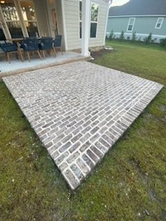 A brick walkway is sitting in the grass in front of a house.