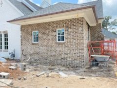 A brick house is being built with a wheelbarrow in front of it.