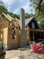 A house is being built with a chimney on the side of it.
