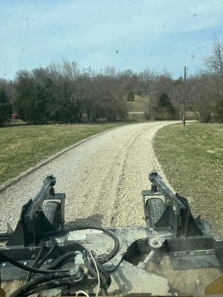 A person is driving a tractor down a dirt road.
