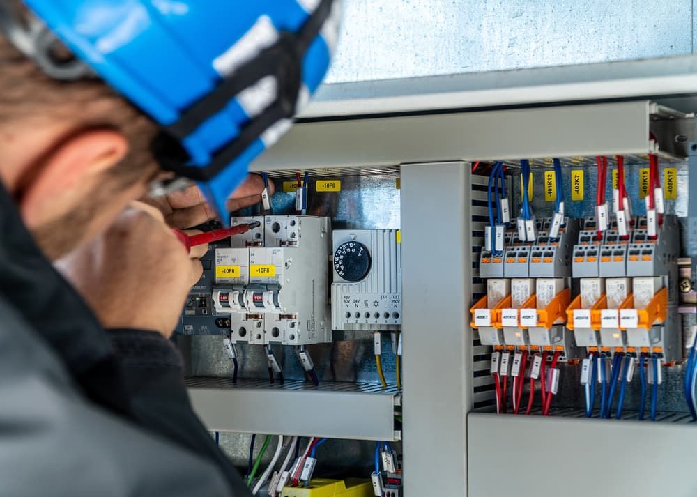 A Man Is Working on A Electrical Box with A Screwdriver — Hantis Electrical Solutions in Shellharbour, NSW