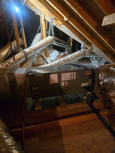 An air conditioner is sitting in the attic of a house.