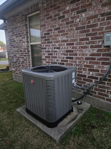 An air conditioner is sitting on the side of a brick building.
