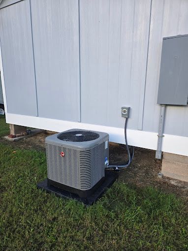 An air conditioner is sitting on the ground next to a building.