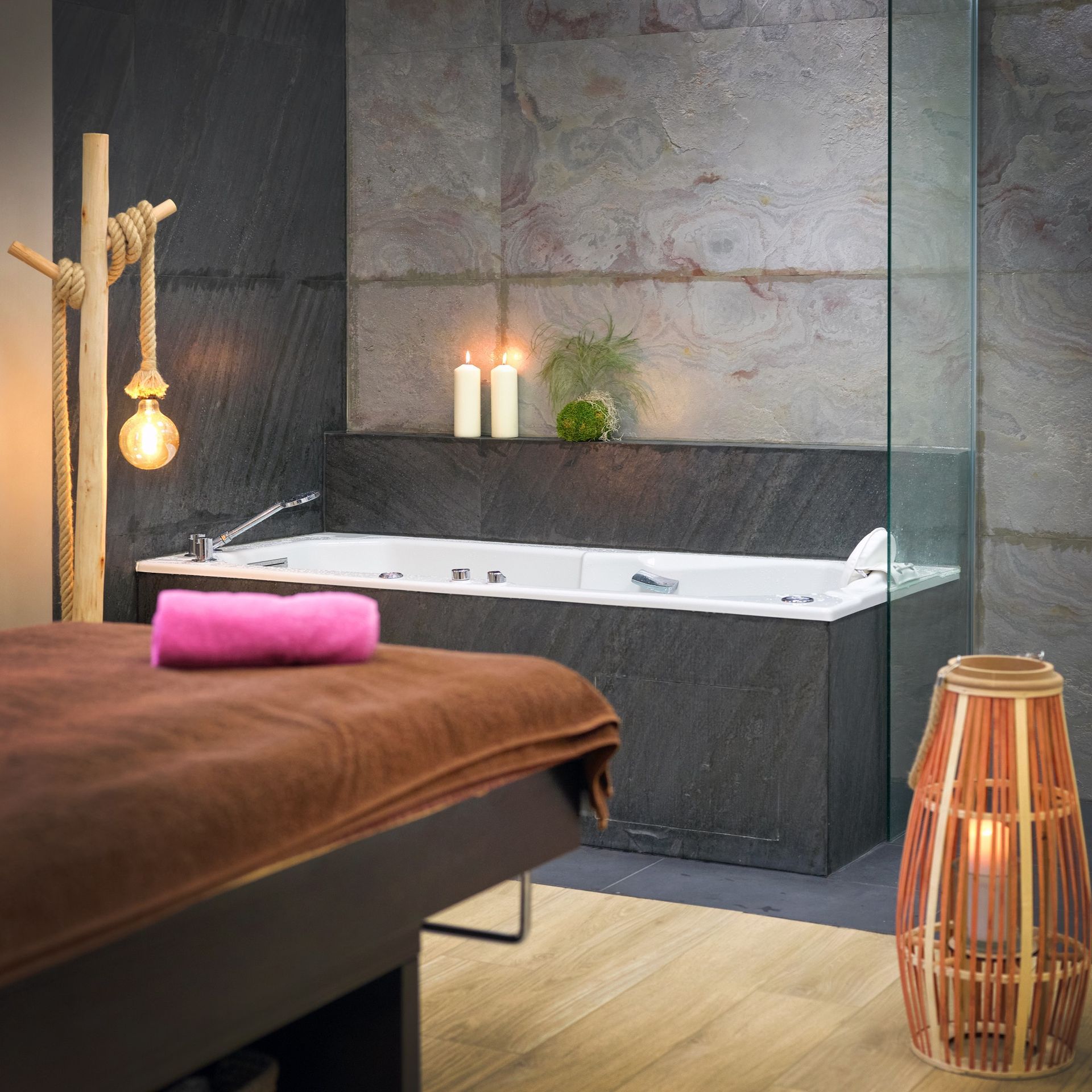 Une salle de bain avec une baignoire et un lit avec une serviette rose dessus