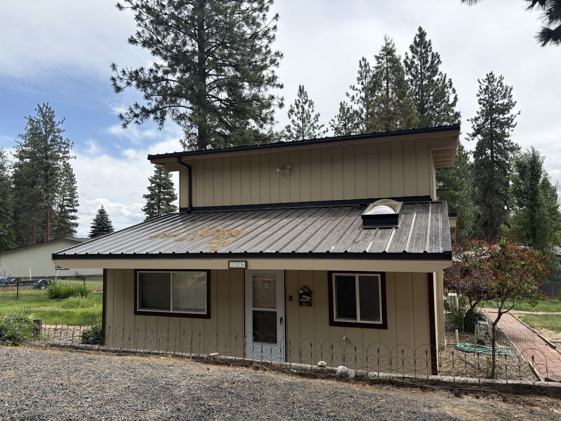 Person in blue coveralls using a drill to install roofing material on a wooden frame.