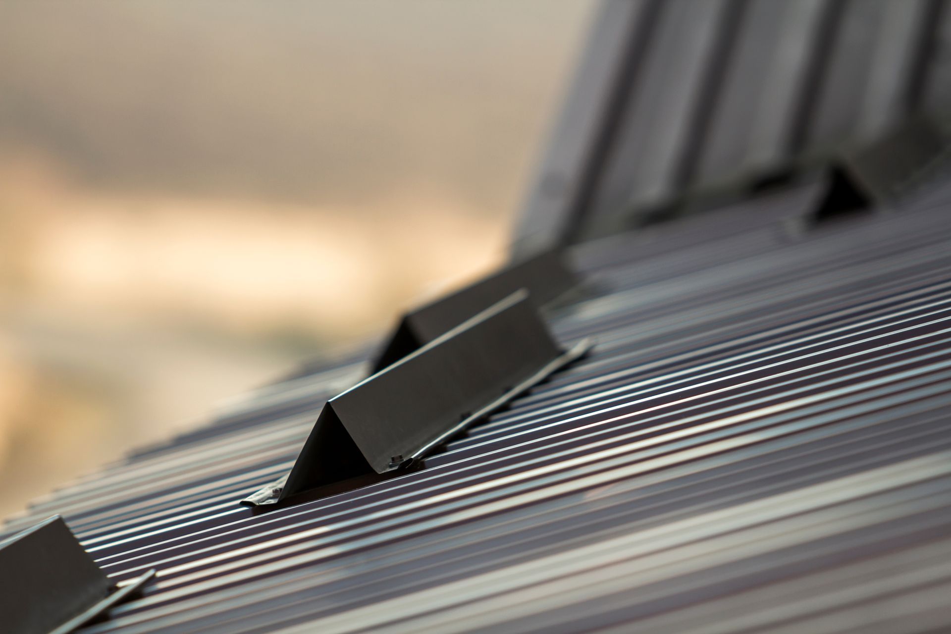 Close-up of a metal roof with V-shaped ridges and supports, gray and black in color.