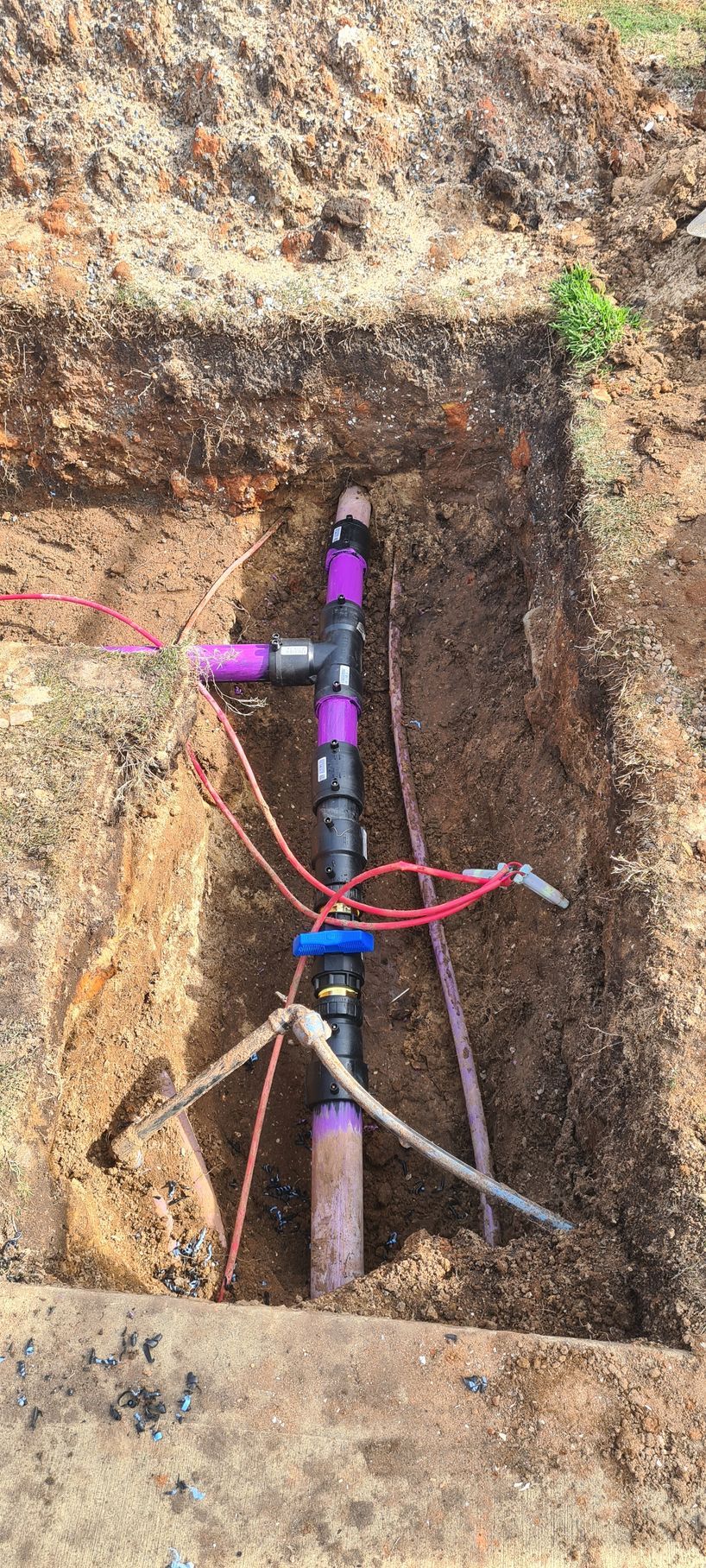 A pipe is sitting in the dirt in a hole.— Midcoast Irrigation & Horticultural Supplies In Wauchope, NSW