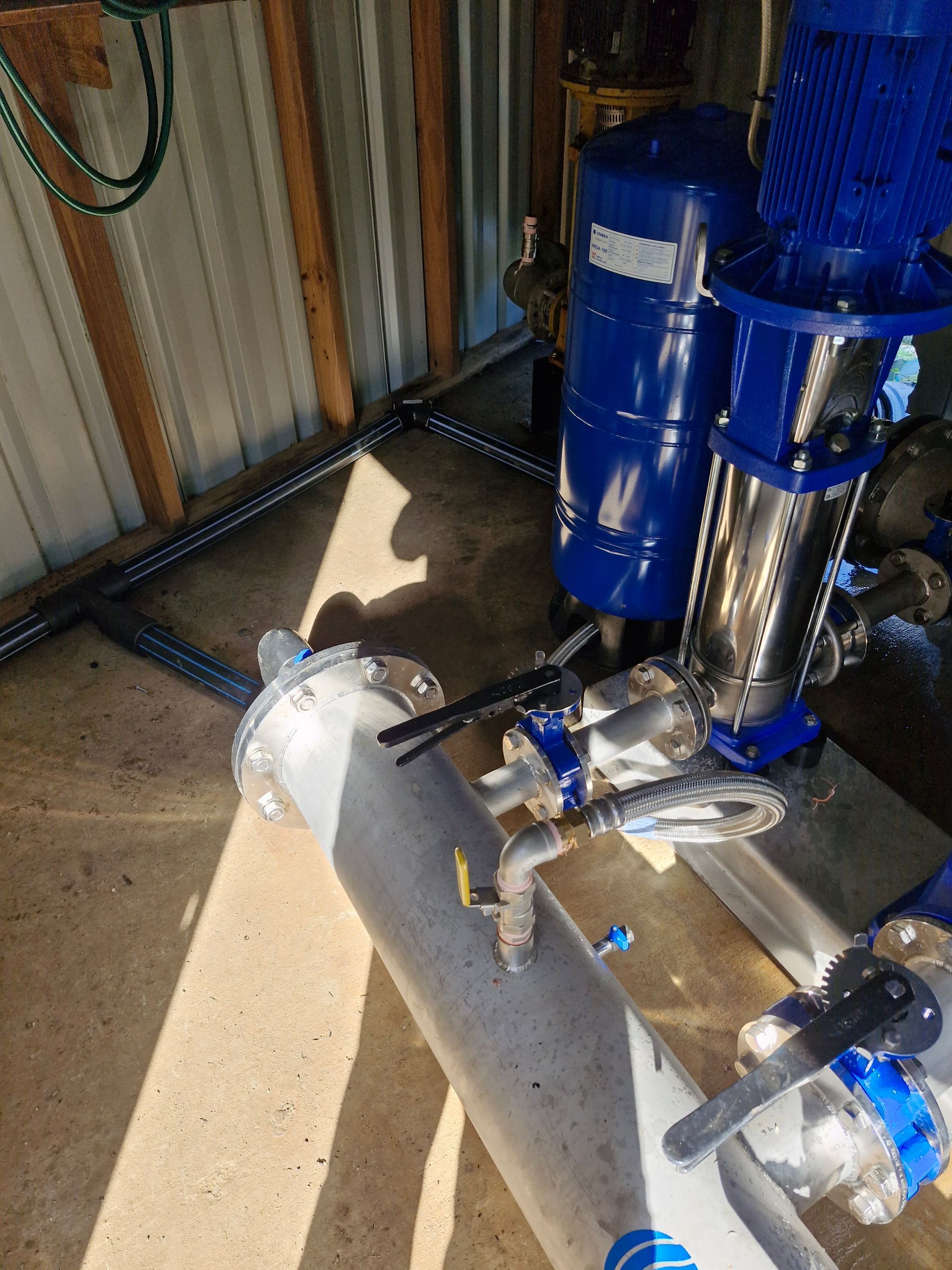 A blue pump is sitting next to a pipe in a room.— Midcoast Irrigation & Horticultural Supplies In Wauchope, NSW