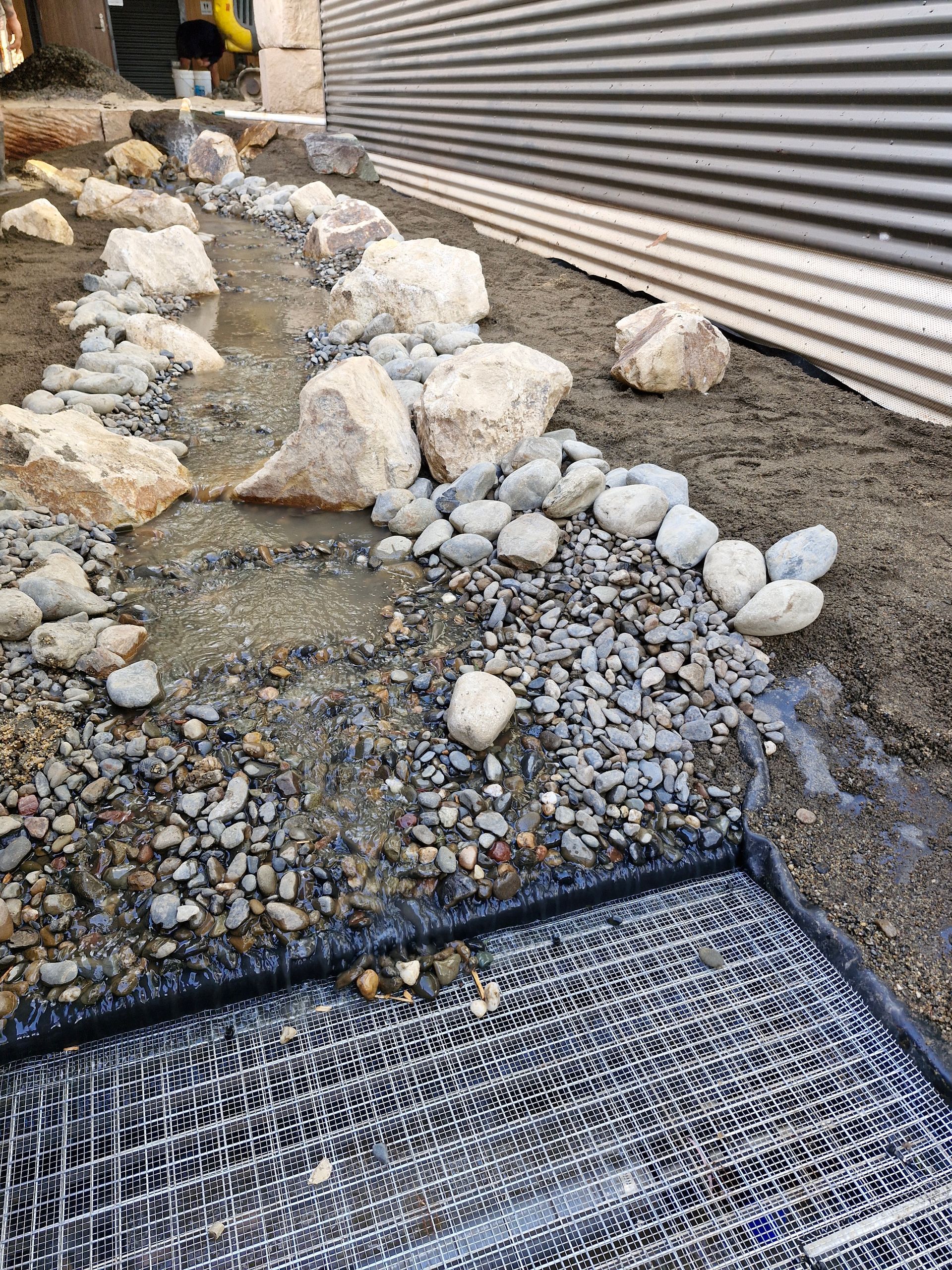 A stream of water is running through a pile of rocks.— Midcoast Irrigation & Horticultural Supplies In Port Macquarie, NSW