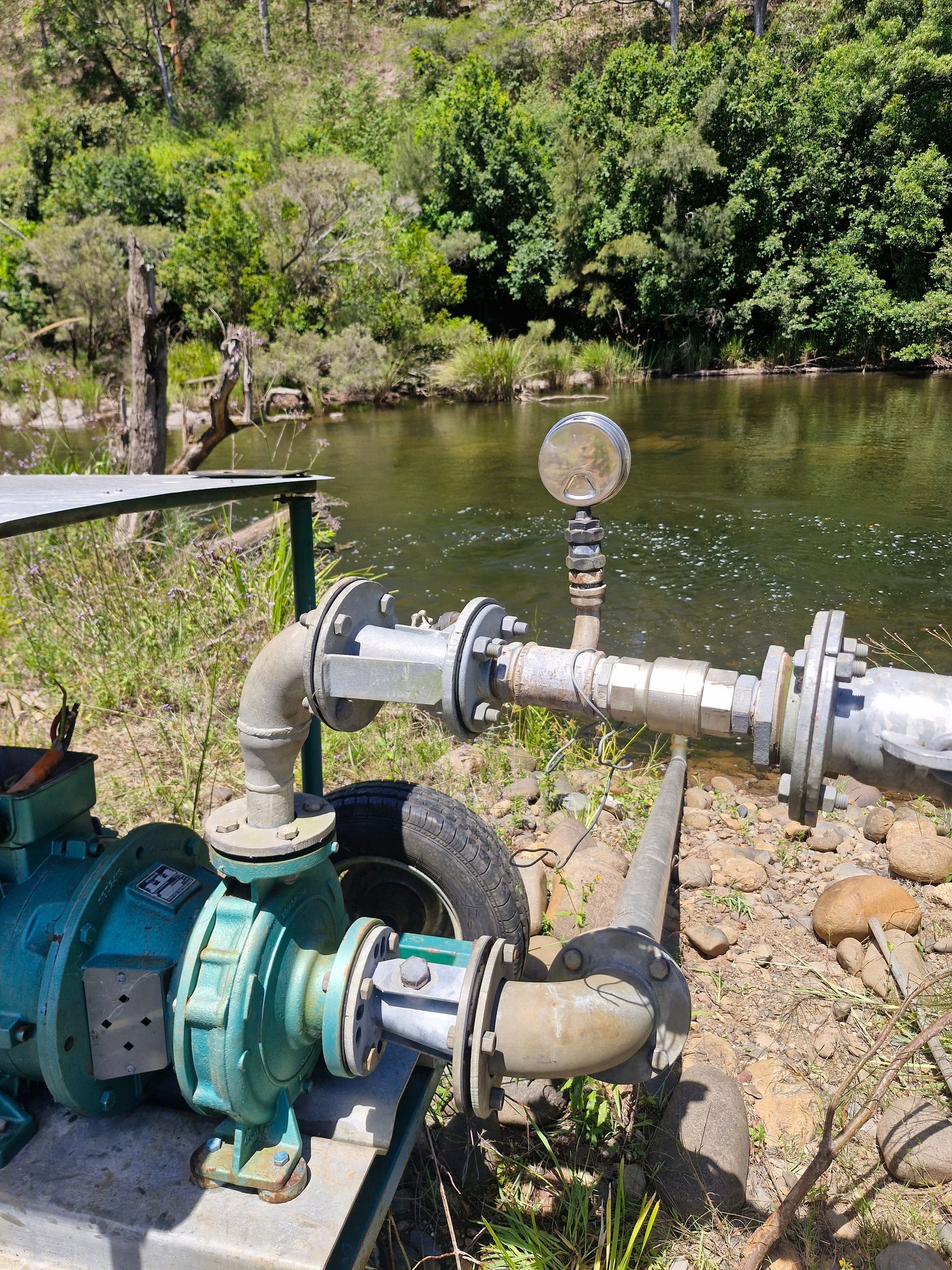 A Close Up Of A Water Pipe With A Red Valve In A Field — Midcoast Irrigation & Horticultural Supplies In Wauchope, NSW