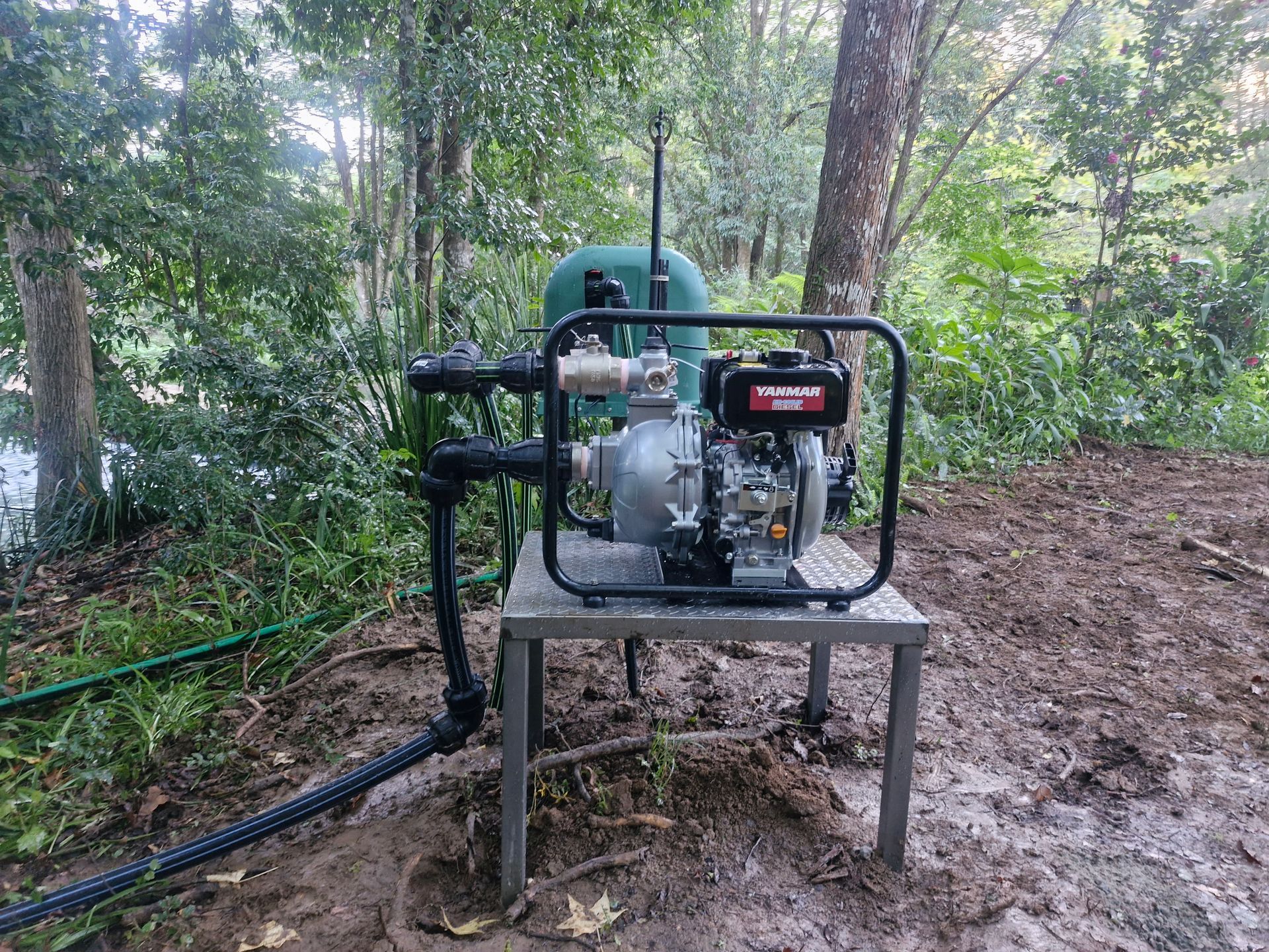 A water pump is sitting on top of a table in the woods.— Midcoast Irrigation & Horticultural Supplies In Wauchope, NSW