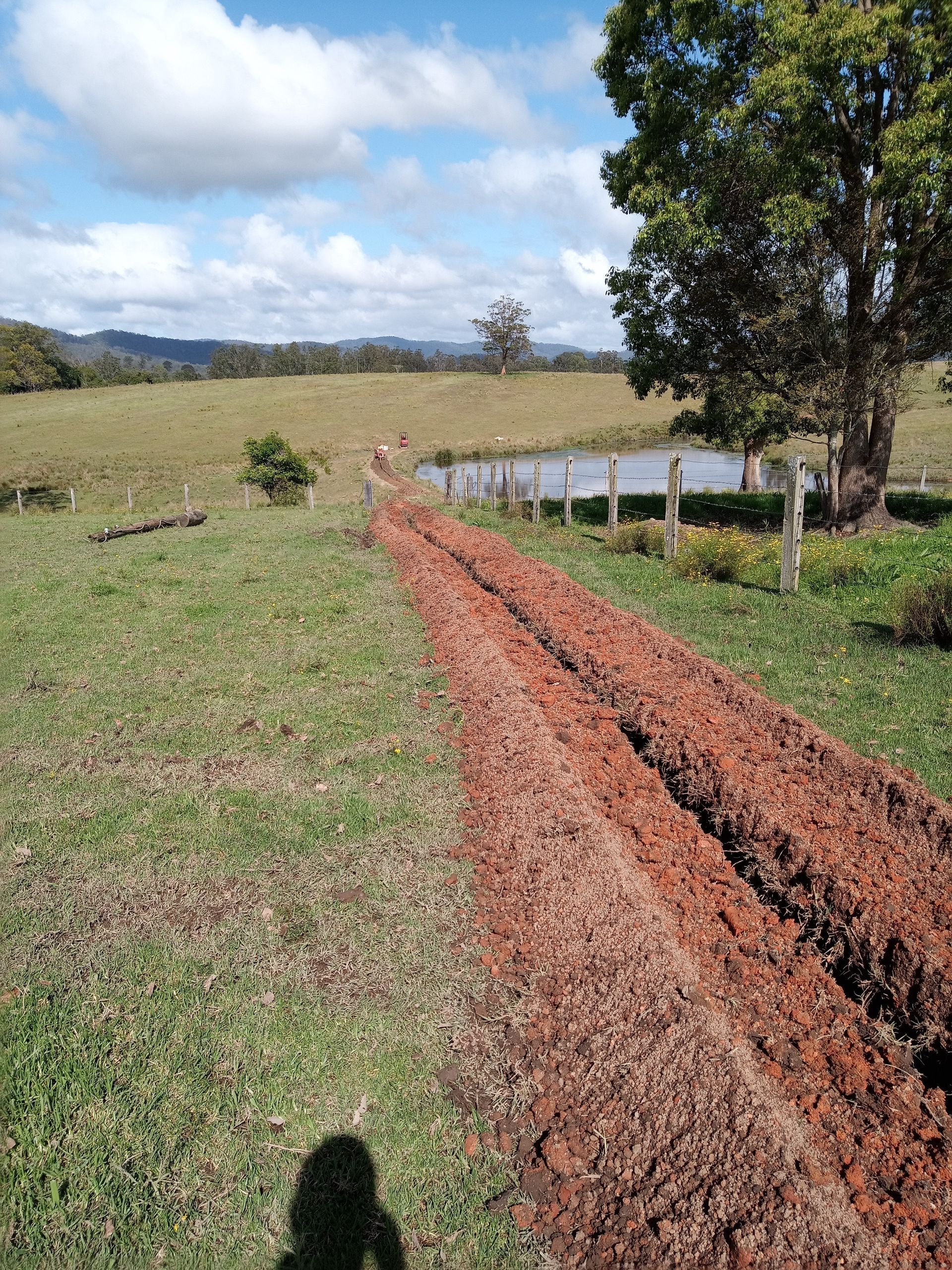 A dirt road going through a grassy field with trees in the background.— Midcoast Irrigation & Horticultural Supplies In Wauchope, NSW