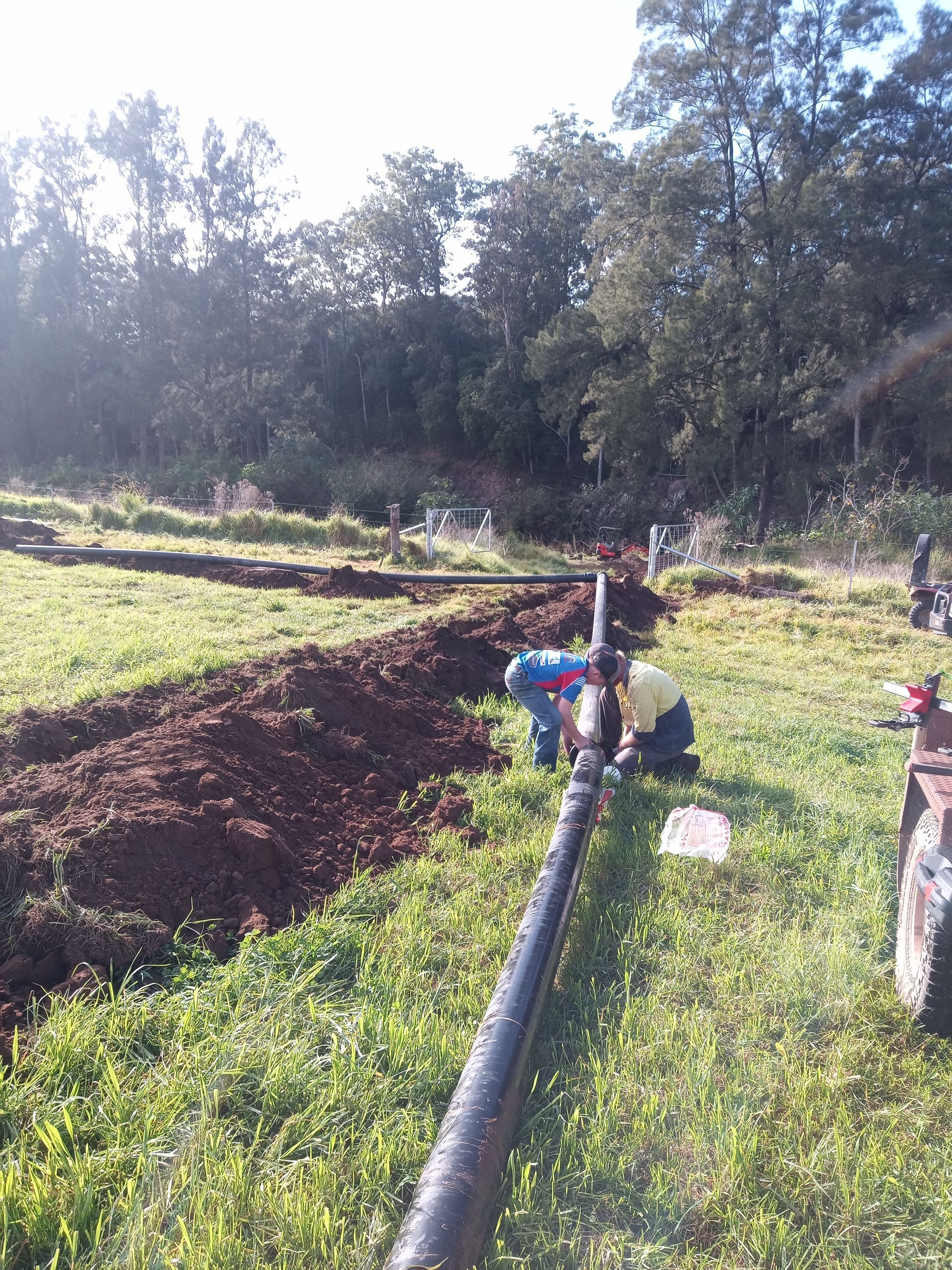A group of people are working on a pipe in a field. — Midcoast Irrigation & Horticultural Supplies In Wauchope, NSW