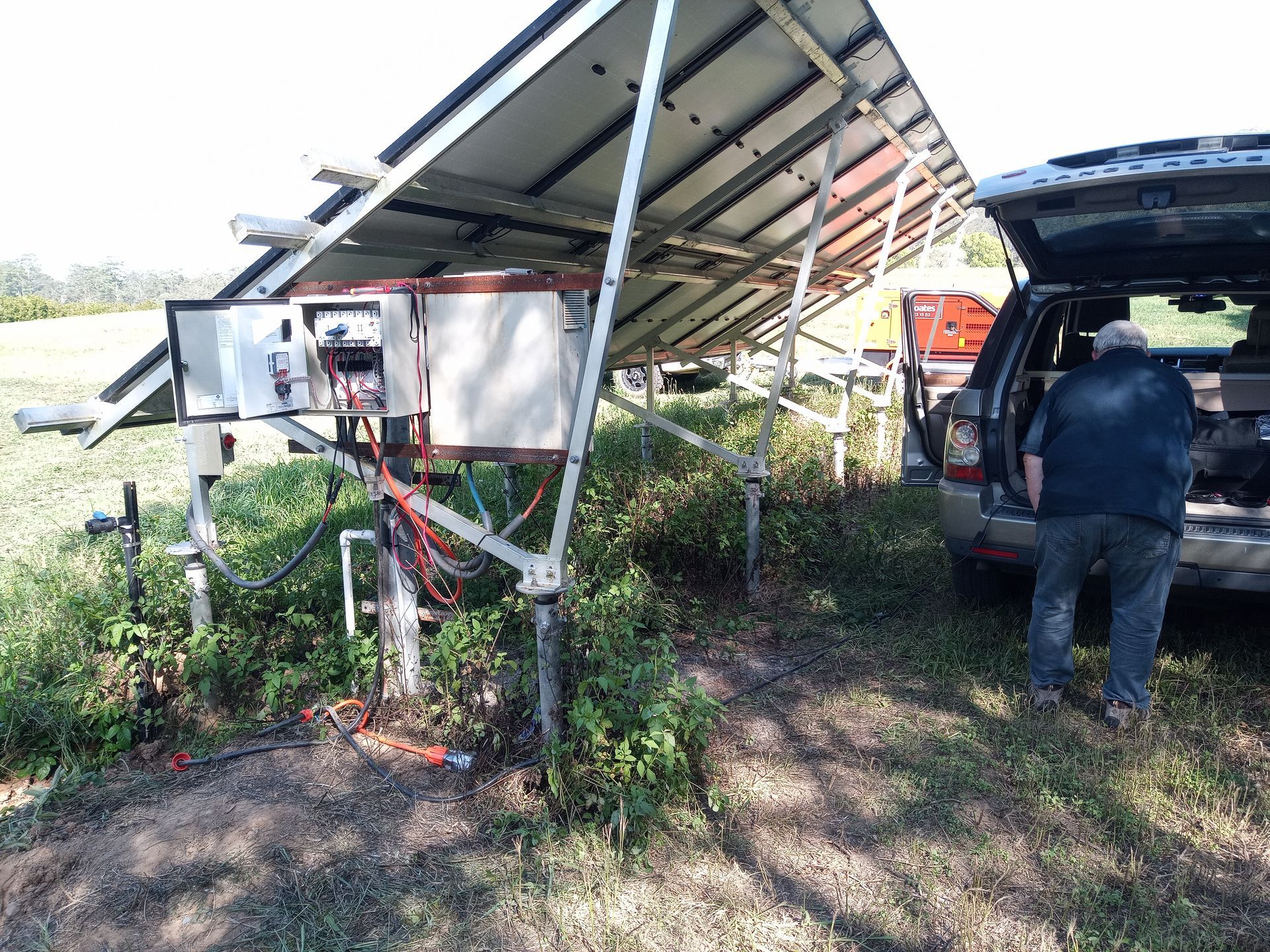 A man is standing next to a car with the trunk open in front of a solar panel. — Midcoast Irrigation & Horticultural Supplies In Wauchope, NSW