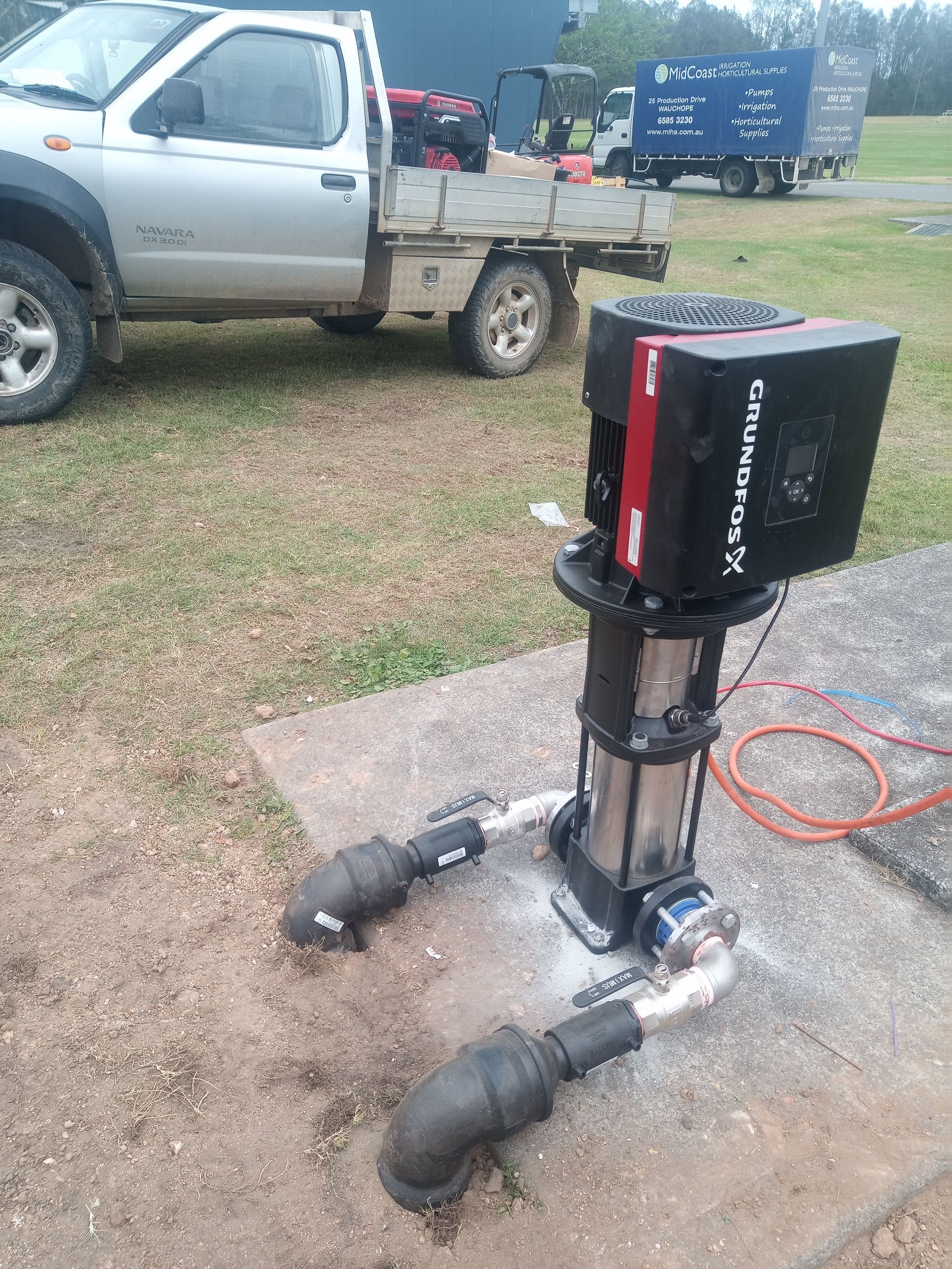 A truck is parked in the grass next to a water pump. — Midcoast Irrigation & Horticultural Supplies In Wauchope, NSW
