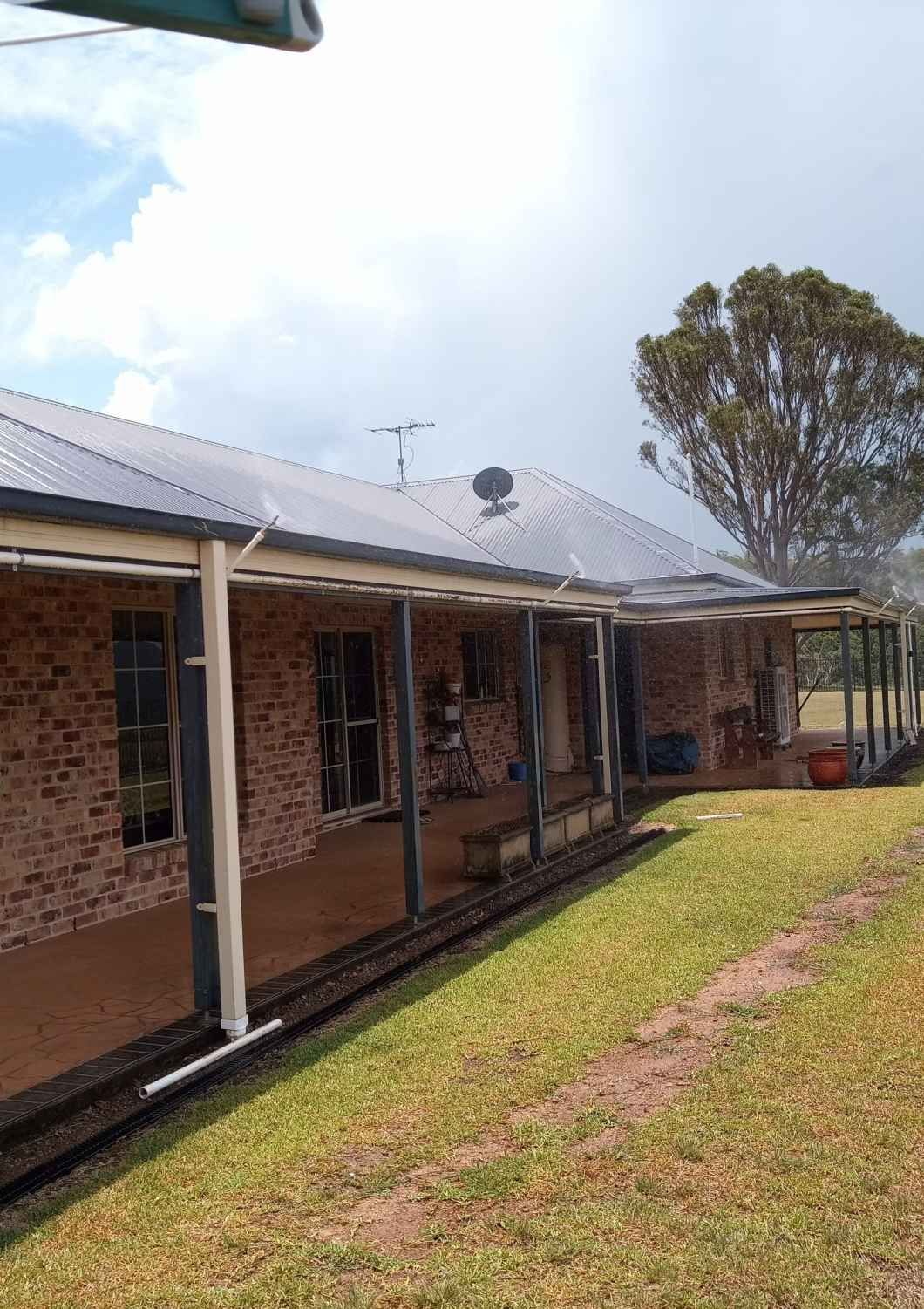 A Brick House With a Porch and a Tree in the Background — Midcoast Irrigation & Horticultural Supplies In Wauchope, NSW