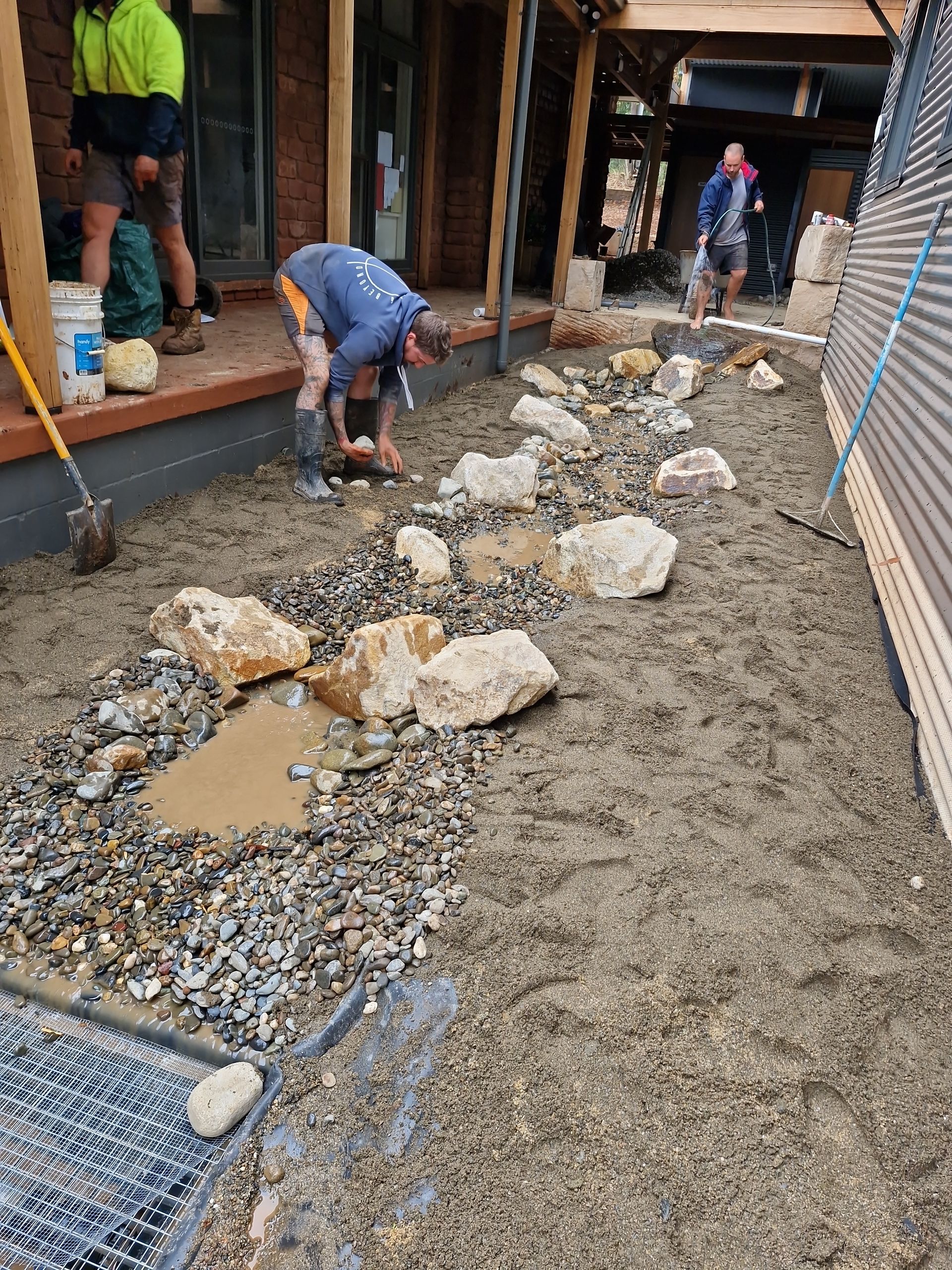 A group of people are working on a rocky area in front of a building. — Midcoast Irrigation & Horticultural Supplies In Kempsey, NSW