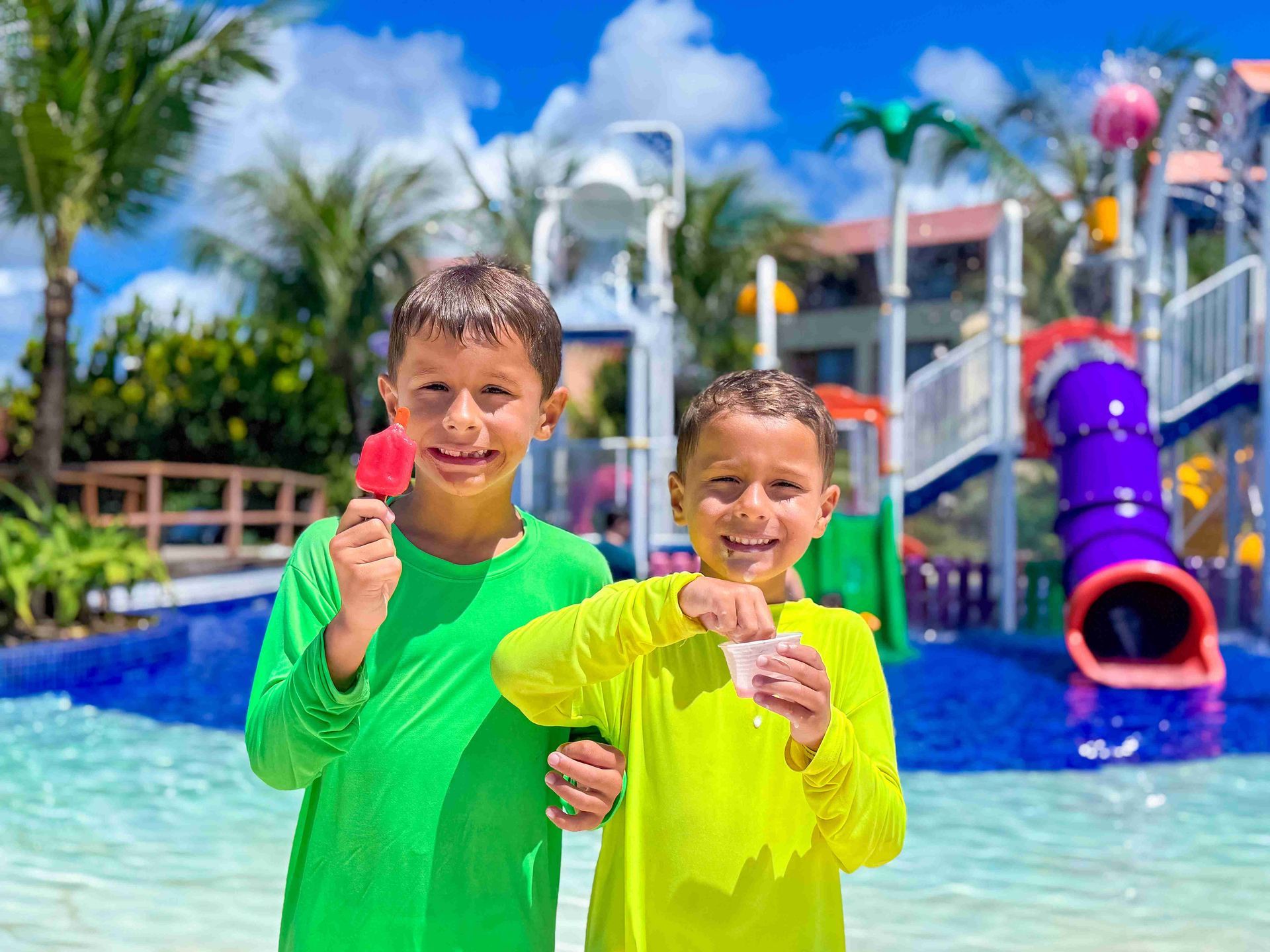 Dois meninos sorridentes tomando picolé na área do parque aquático infantil do resort all inclusive Enotel Porto de Galinhas