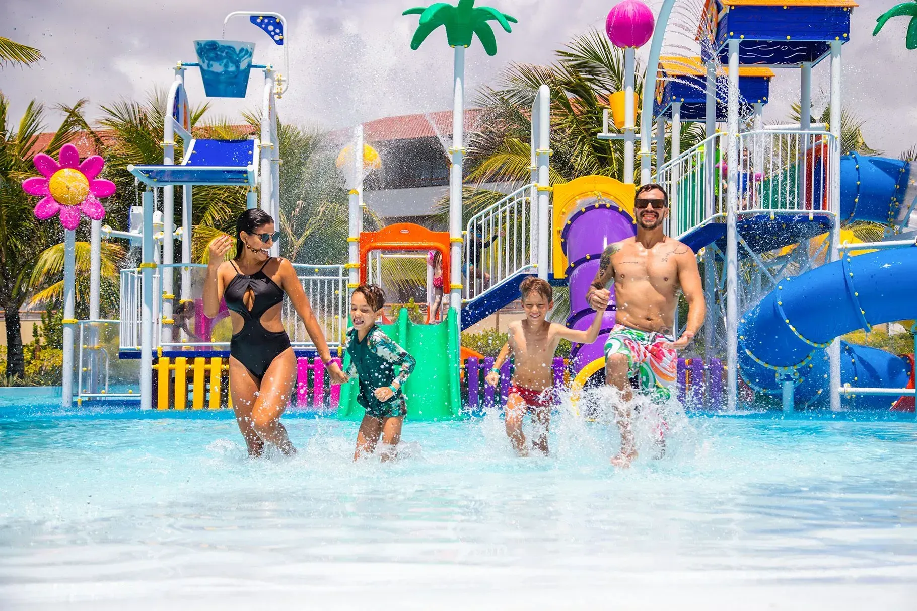 Família com dois filhos correndo e se divertindo na piscina do parque aquático infantil do resort all inclusive Enotel Porto de Galinhas
