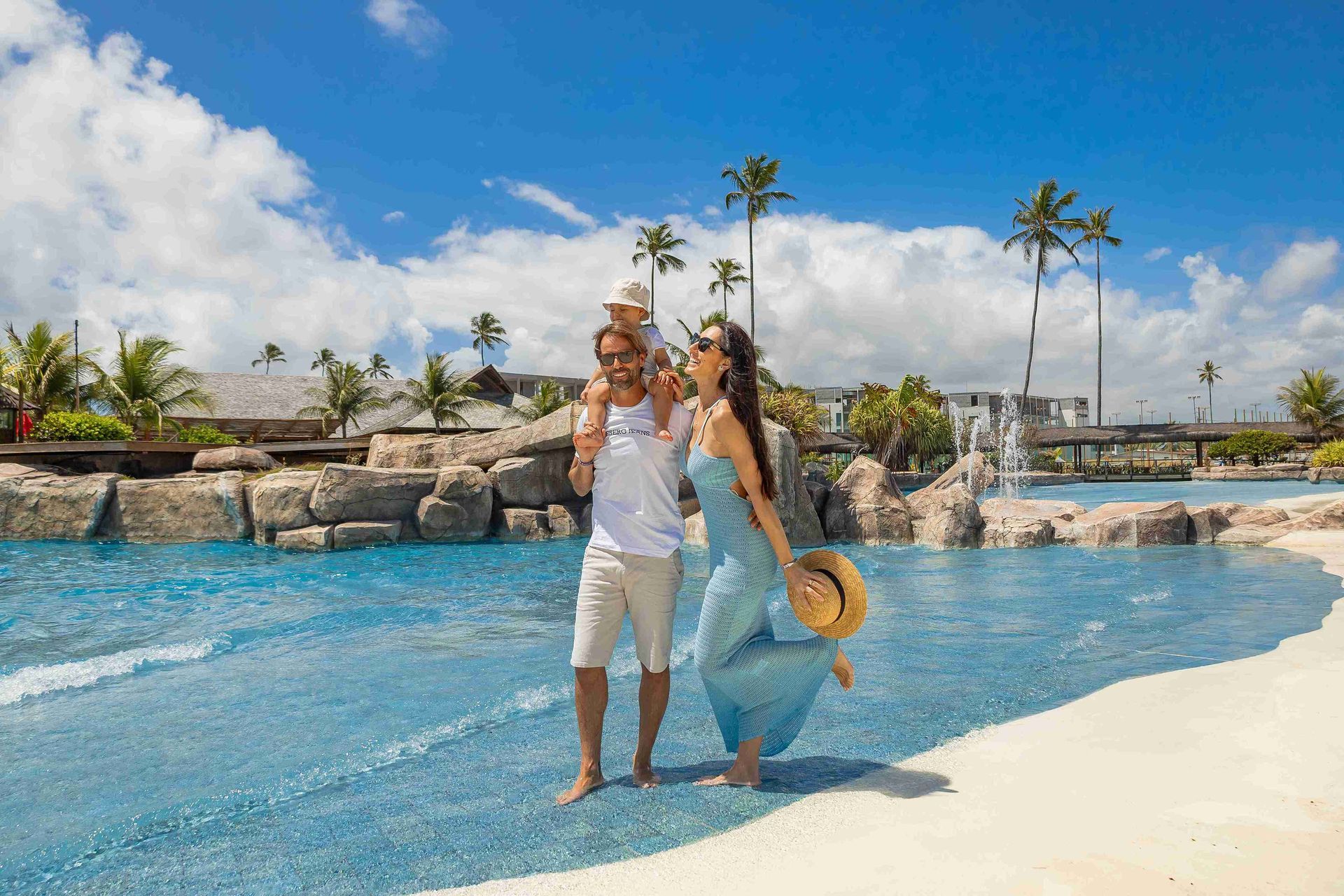 Família feliz com dois filhos sorrindo sob arco de bambu na área de lazer do resort all inclusive Enotel Porto de Galinhas