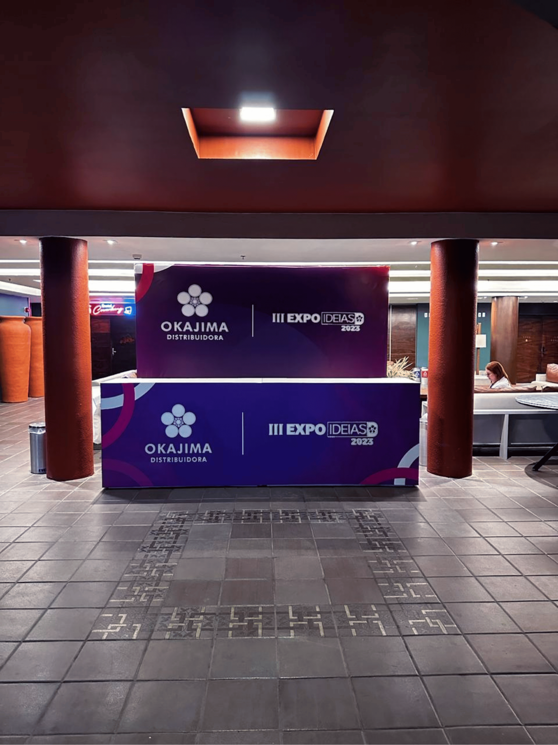 Balcão e portal roxo de credenciamento personalizado para a III Expo Ideias Okajima posicionado no Foyer Francisco Brennand