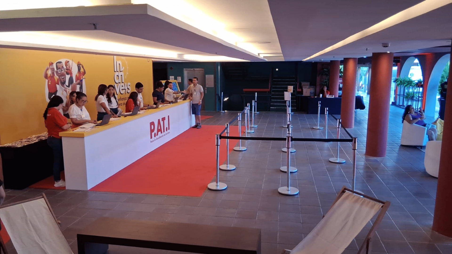 Balcão de atendimento e credenciamento linear com a inscrição "P.A.T.I." e parede decorativa amarela no Foyer Luiz Gonzaga