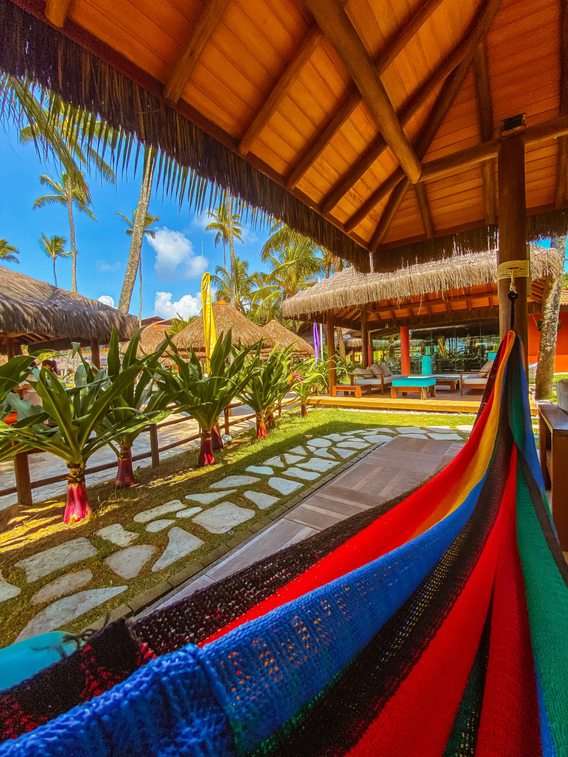 Rede de descanso colorida instalada em quiosque de palha com vista para os jardins e coqueirais do Enotel Porto de Galinhas