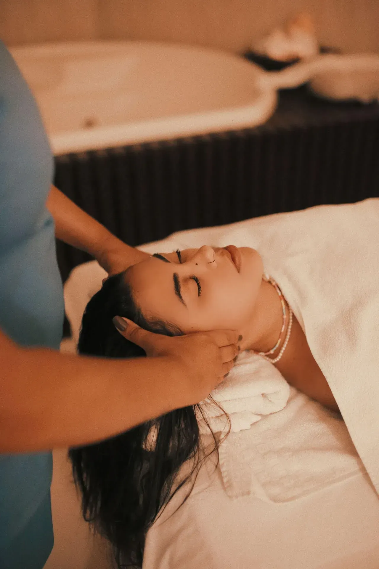 Mulher recebendo massagem relaxante na cabeça em sala de spa de resort